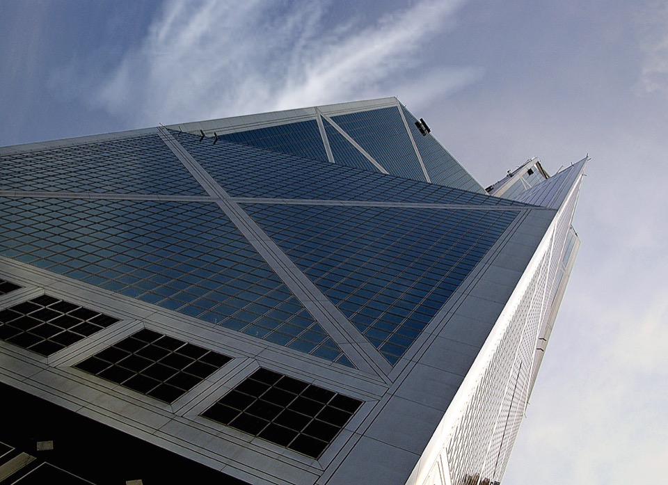 The Bank of China Tower in Hong Kong, its triangular facets rising against open sky.