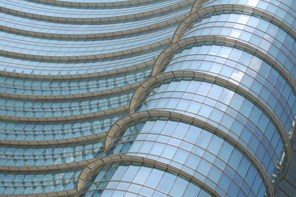 A curved glass facade, the panels bending away from the viewer in a single unbroken run.